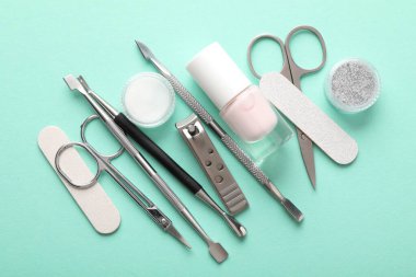Turkuaz zemin üzerinde farklı manikür araçları kümesi, düz yatar