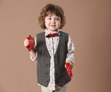 Kahverengi arka planda oyuncak tef çalan sevimli küçük çocuk.