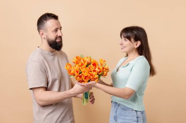 Adam bej arka planda sevgili karısına güzel laleler sunuyor.