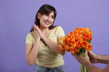 Mor arka planda sevgilisine kırmızı güller sunan bir adam, yakın plan.