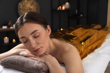 Vücuduna termal folyo örten kadın spa salonunda tedavi görüyor.