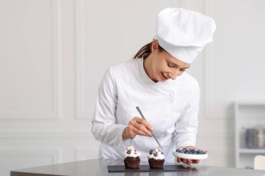 Şekerci mutfakta yabanmersinli kek dekore ediyor.