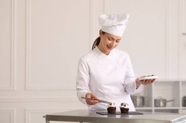 Şekerci mutfakta yabanmersinli kek dekore ediyor.