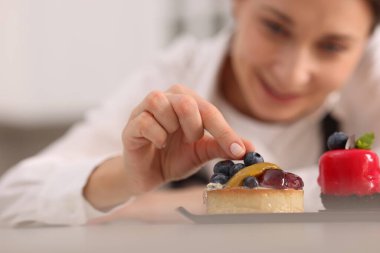 Sofrada yaban mersinli tart dekorasyonu yapan şekerci, seçici odak