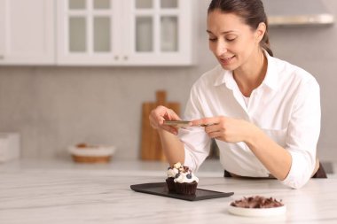 Şekerci masada lezzetli keklerin fotoğrafını çekiyor, mesaj atmak için yer var.