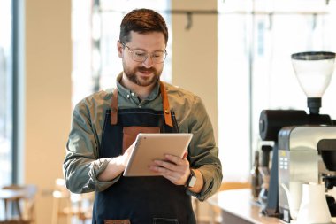 Kafesinde tabletle çalışan yakışıklı bir işletme sahibi.