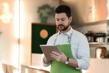 Kafesinde tabletle çalışan yakışıklı bir işletme sahibi. Metin için boşluk