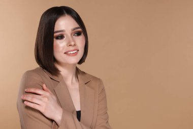 Güzel, genç ve mutlu bir kadının portresi. Bej arka planda harika düz saçları var. Mesaj atmak için yer var.