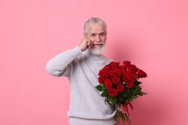 Pembe arka planda kırmızı gül buketi olan son sınıf öğrencisi.