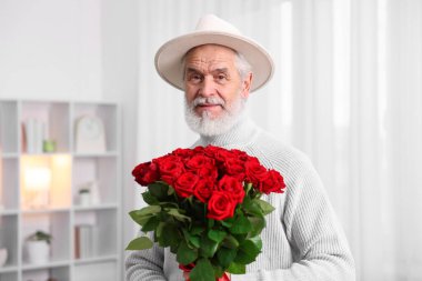 Evde elinde kırmızı güllerle kıdemli bir adam var.