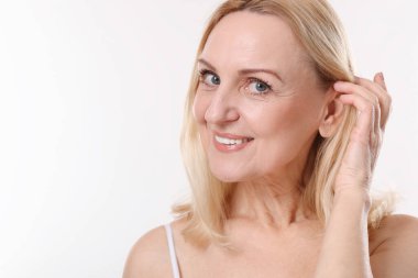 Beyaz arka planda gülümseyen orta yaşlı kadın portresi. Metin için boşluk