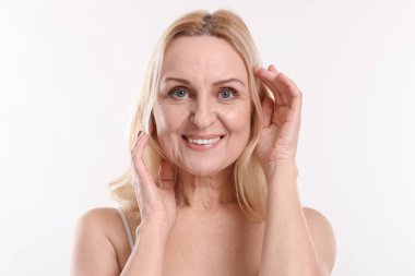 Beyaz arka planda gülümseyen orta yaşlı kadın portresi