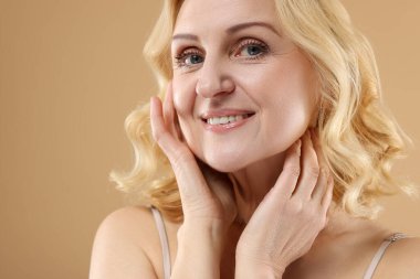 Bej arka planda gülümseyen orta yaşlı kadın. Metin için boşluk