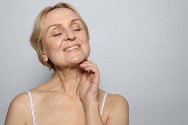 Gri arka planda gülümseyen orta yaşlı kadın. Metin için boşluk