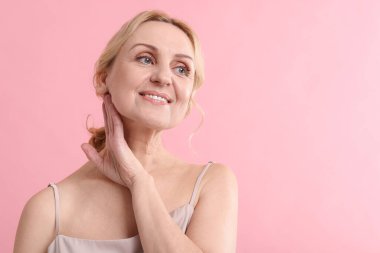 Pembe arka planda gülümseyen orta yaşlı kadın. Metin için boşluk