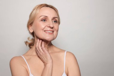 Gri arka planda gülümseyen orta yaşlı kadın. Metin için boşluk