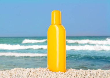 Okyanus kıyısındaki sahilde bir şişe güneş kremi.