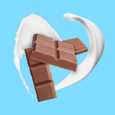 Nefis çikolata parçaları ve açık mavi arka planda havada sütün damlaları.