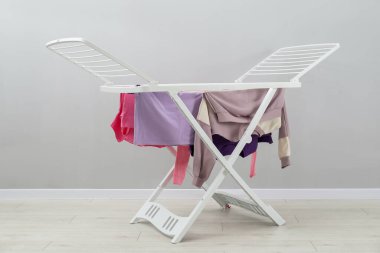 Gri duvarın yanında temiz çamaşırları olan kuru askı.