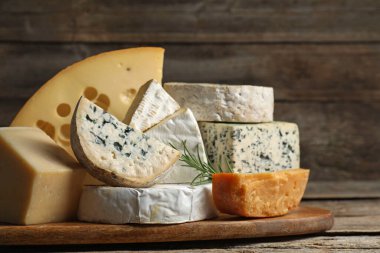 Ahşap masada farklı peynir ve biberiye çeşitleri, yakın plan.