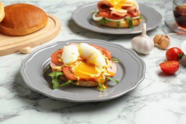 Lezzetli bir kahvaltı. Haşlanmış yumurta, jambon, domates, roka ve ekmek beyaz mermer masada, yakın plan.