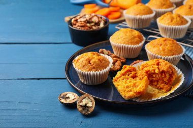 Lezzetli havuçlu kekler ve cevizler mavi ahşap masada, yakın plan. Metin için boşluk