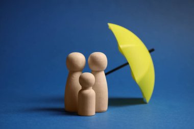 Mavi arka planda şemsiye altında insan figürleri. Sigorta konsepti