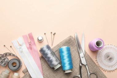 Açık pembe arka planda farklı dikiş malzemeleri, düz bir zemin. Metin için boşluk
