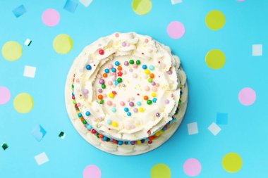 Rengarenk serpiştirilmiş nefis bento keki ve açık mavi masada konfeti.