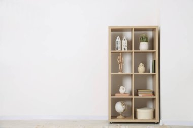 Shelving unit with different home decor near white wall indoors, space for text