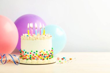 Renkli serpilmiş nefis bento keki ve gri arka planda yanan mumlar. Metin için boşluk