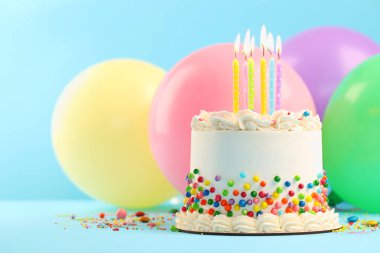 Renkli şekerli nefis bento keki ve açık mavi masada yanan mumlar, yakın plan. Metin için boşluk