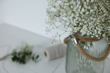Beautiful gypsophila flowers in vase on white table, closeup. Space for text