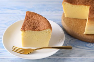 Tasty Japanese Castella sponge cake and fork on light blue wooden table, closeup