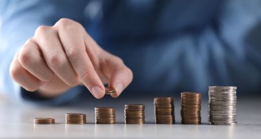 Adam açık gri masadaki bozuklukların üzerine para koyuyor, yakın plan.