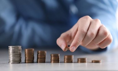 Adam açık gri masadaki bozuklukların üzerine para koyuyor, yakın plan.