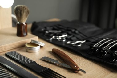 Berber dükkanında, açık ahşap masanın üzerinde birçok farklı berber aleti var.