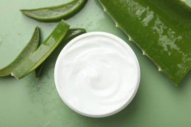 Aloe vera özütüyle nemlendirici krem, yeşil arkaplanda yapraklar ve su damlaları, düz bir zemin