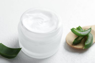 Aloe vera özütüyle nemlendirici krem ve beyaz desenli arka planda yapraklar, yakın plan