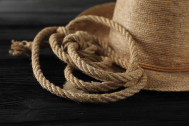 Siyah ahşap arka planda pamuk ip ve hasır şapka, yakın plan.