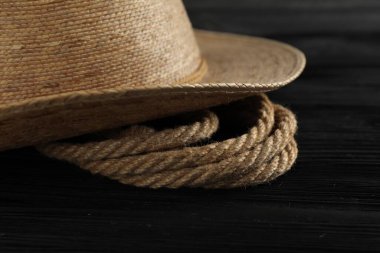 Siyah ahşap arka planda pamuk ip ve hasır şapka, yakın plan.