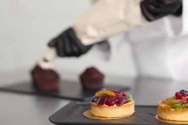 Şekerlemecinin masada kremayla kapkek süslemesi, seçici odaklanma