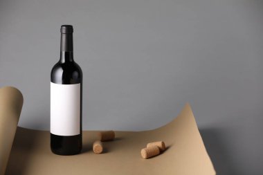 Mantarlı bir şişe şarap ve gri arka planda kağıt. Metin için boşluk