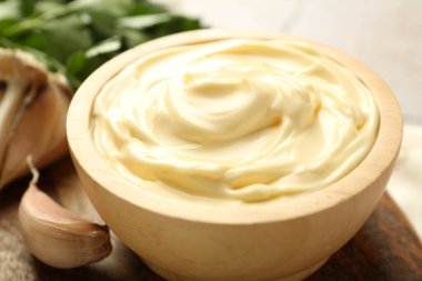 Lezzetli mayonez sosu kasede ve sarımsak masada, yakından.