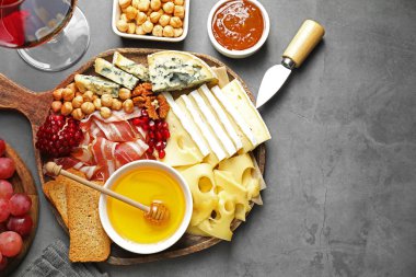 Farklı kesim peynir türleri ve şarapla servis edilen diğer atıştırmalıklar gri desenli masa, düz yatak. Metin için boşluk