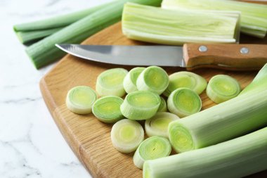 Kırpılmış pırasa, beyaz mermer masa üzerinde bıçak ve tahta, yakın plan.