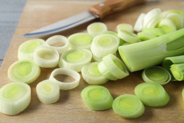 Taze kesilmiş pırasa ve bıçak ahşap masada, yakın plan.