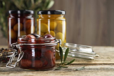 Cam kavanozlarda zeytin turşusu ve ahşap masada baharatlar, yakın plan. Metin için boşluk