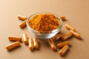 Bej arka planda zerdeçal kapsülleri ve toz, yakın plan