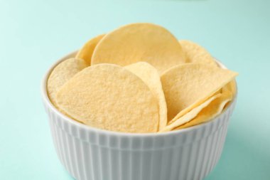 Açık mavi arka planda leziz patates cipsi, yakın plan.